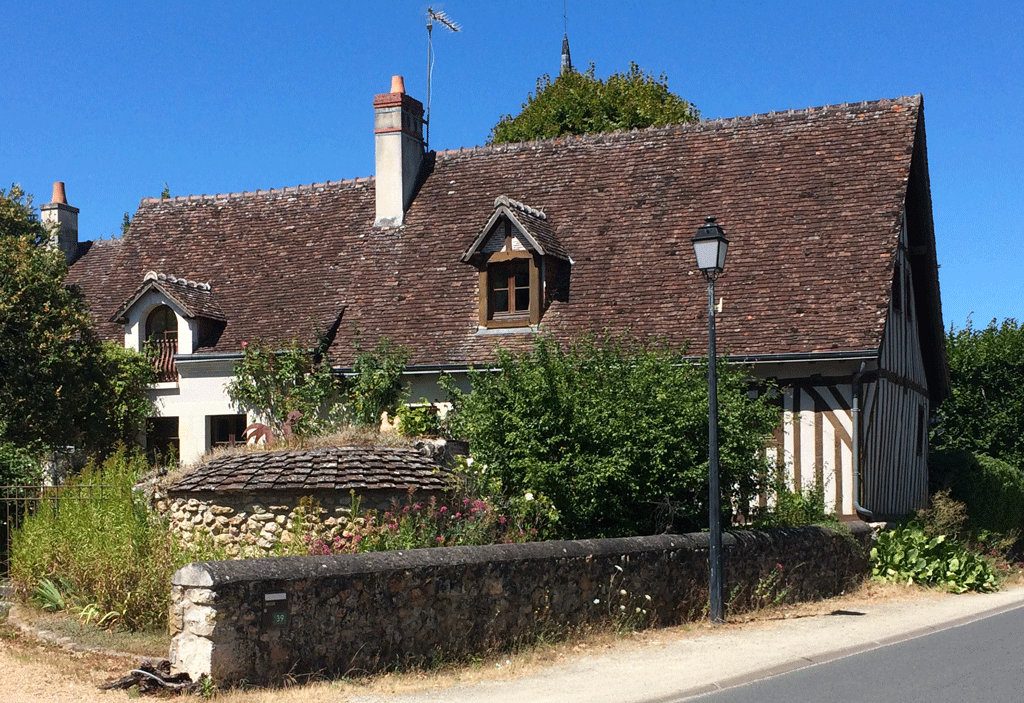 A half-timbered house with an outside bread oven in the foreground in Vieux Bourg