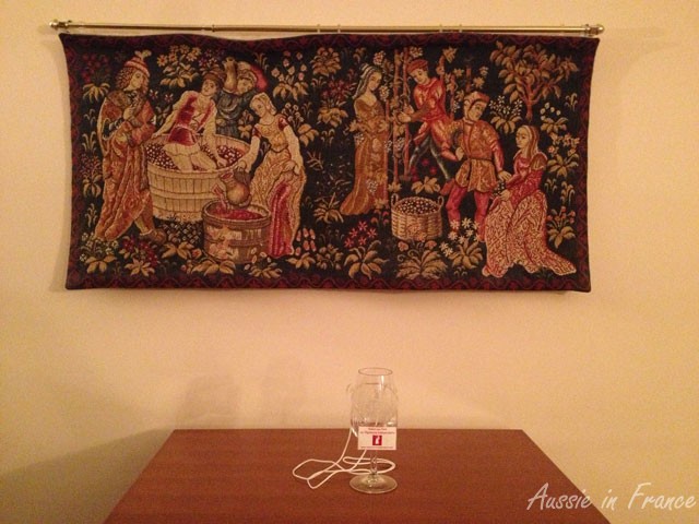Inao glass with its holder. In the background is a tapestry based on one in the Cluny mediaeval museum in Paris