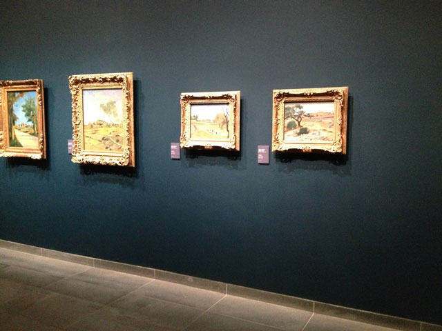 Paintings from the permanent collection on the wall inside the museum