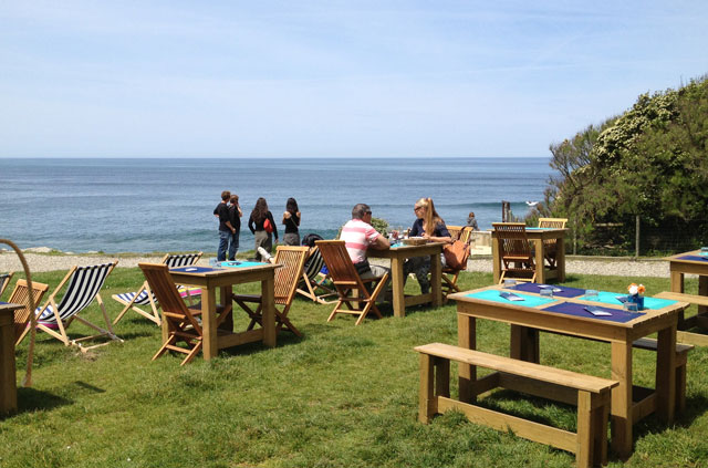 Tables and deck chairs on the grass at Le O
