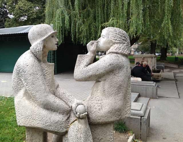 Statues in the park with chess players in the background